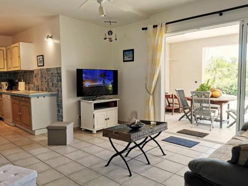 a living room with a tv and a kitchen with a table at Le Colibri d'isa in Capesterre-Belle-Eau