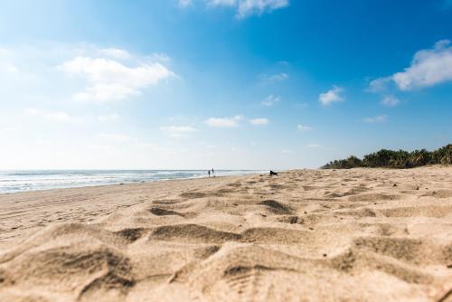 a sandy beach with people walking on the beach at Alberca, Playa Cercana & Club de Playa opcional -Departamento E13D302 in Gallinero