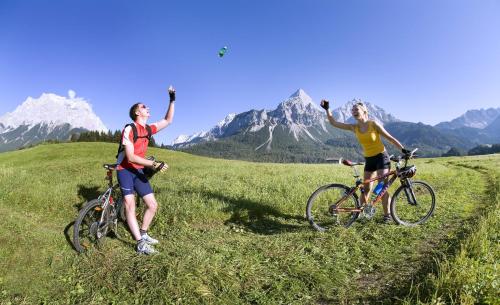 two people riding bikes on a hill with their hands in the air at der grüne Baum Mountain Boutique Hotel in Ehrwald