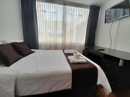 a bedroom with a bed with a desk and a window at Habitacion doble in Arequipa