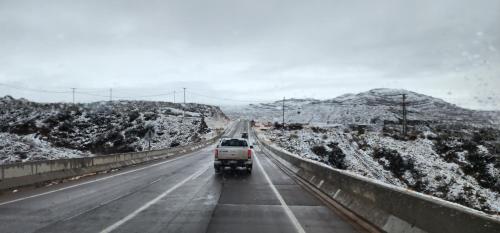 a truck driving down a highway with snow covered mountains at Cerro Indio in Potrerillos
