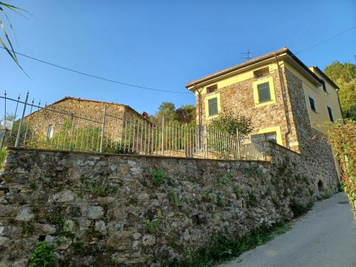 a house on a stone wall with a fence at Il Fontolo in Ponzano Superiore