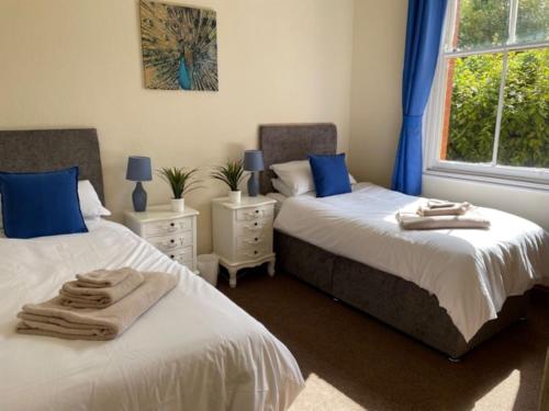 twee bedden in een slaapkamer met blauwe kussens erop bij The Castle Apartment, Lots of Character Cosy and Comfortable, Private Garden and FREE Parking in Nottingham