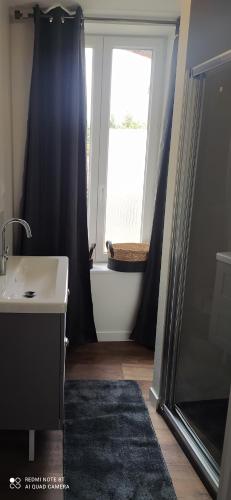 a bathroom with a sink and a tub and a window at gite de La place de l'église in Sainte-Mère-Église