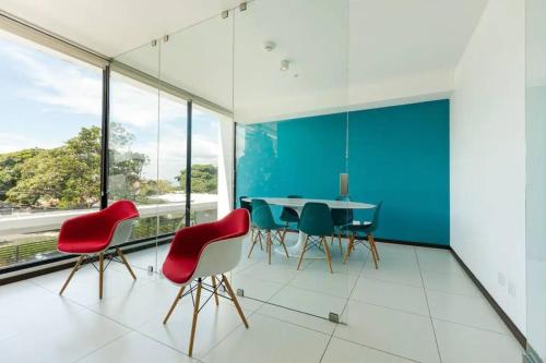 a dining room with red chairs and a blue wall at Rooftop Jacuzzi - 18th Floor Apt City View in Mata de Palo