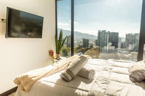 a bedroom with a large white bed with a large window at Rooftop Jacuzzi - 18th Floor Apt City View in Mata de Palo