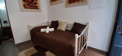 um quarto com uma cama com lençóis e almofadas castanhos em Casa das Matriarcas - Casa da Avó Elisinha em Belmonte