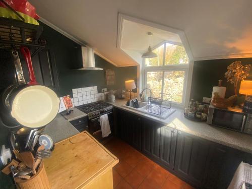 a kitchen with black cabinets and a sink and a window at Cardiff - Home from Home in Cardiff