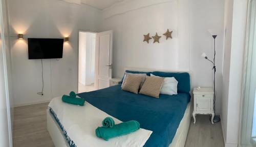um quarto com uma cama azul e branca e uma televisão em Sun & Sea rooftop em Costa da Caparica