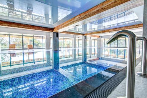 a large swimming pool with blue tiles in a building at Panorama in Krynica Zdrój