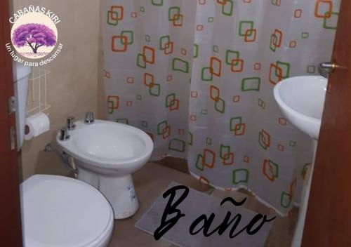 Un baño con inodoro, lavabo y cortina de ducha. en Cabañas Kiri, en Santa Rosa de Calamuchita