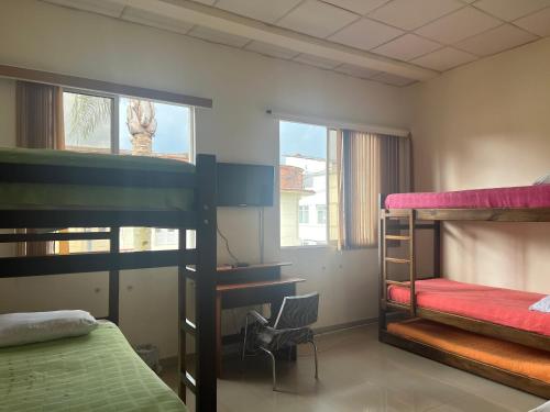 1 dormitorio con 2 literas y escritorio en Hostal Zaguán Caldense, en Manizales