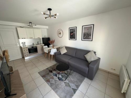 un salon avec un canapé et une cuisine dans l'établissement Cosy 2 pièces à 1min à pied de la plage et proximité de la gare de train, à Juan-les-Pins