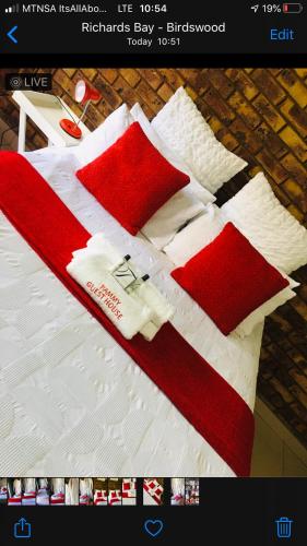 a bed with red and white blankets and pillows on it at Pammy Guest House in Richards Bay