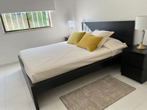 een slaapkamer met een bed met gele kussens en een raam bij Pateo AL Albufeira in Albufeira