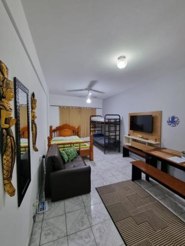 a living room with a couch and a flat screen tv at Kitnet Ubatuba in Ubatuba