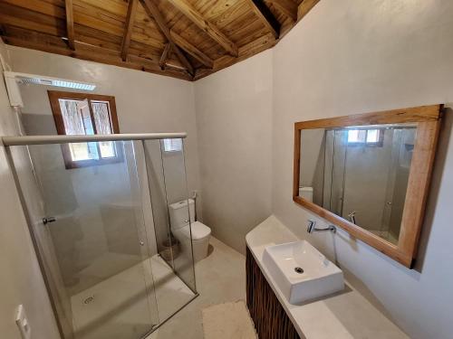 uma casa de banho com uma cabina de duche em vidro e um lavatório. em Pousada D'Oxum Caraíva em Caraíva