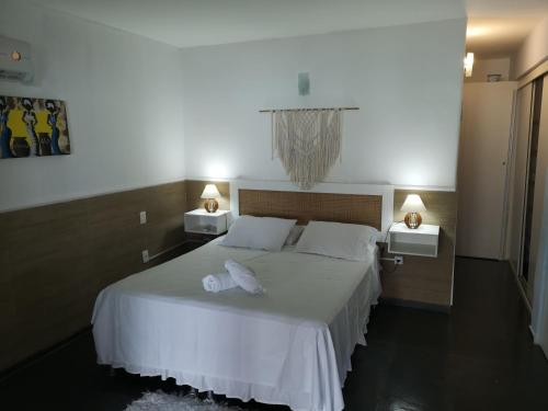 1 dormitorio con 1 cama blanca y 2 mesitas de noche en Coco Beach Apart, en Natal