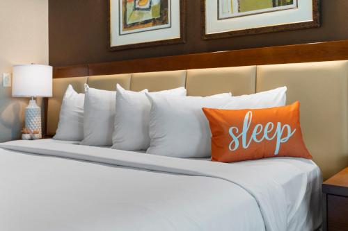 a large bed with white pillows and orange pillows at Lucky Gem Penthouse & Luxury Suites at Signature Resort, Balcony Strip View 1607 in Las Vegas