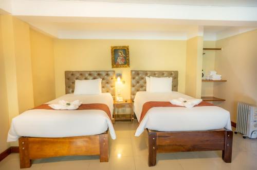 a bedroom with two beds with white sheets at Santuario Machupicchu in Machu Picchu