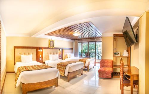 a hotel room with three beds and a flat screen tv at Santuario Machupicchu in Machu Picchu