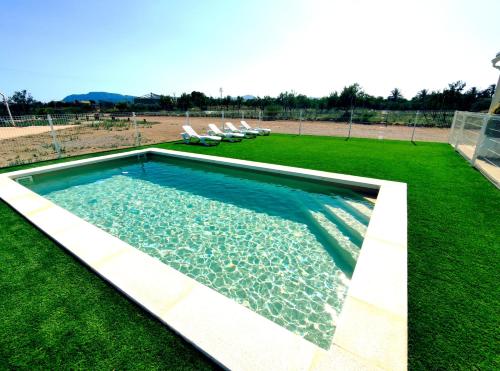 ein Schwimmbad in der Mitte eines Grasfeldes in der Unterkunft Casa Rural Villa Arizona en Cartagena in Murcia