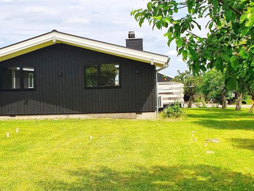 una casa negra en un patio con césped verde en 6 person holiday home in Str by en Køge