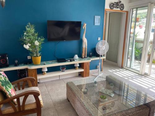 a living room with a blue wall with a tv at Duplex Marigot centre-ville in Marigot