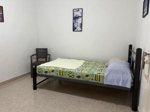 a small bed in a room with two chairs at Helena Hostel in Cali