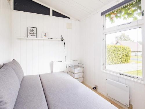 a white bedroom with a bed and a window at Holiday home Karrebæksminde VI in Karrebæksminde