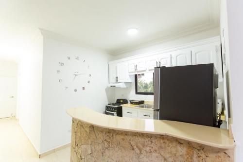 a kitchen with white cabinets and a black refrigerator at MB Apartment - B in San Felipe de Puerto Plata