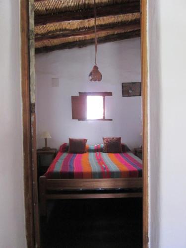 a bedroom with a bed with a colorful blanket at La Calabaza Cabaña in Tilcara