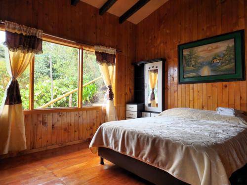 um quarto com uma cama e uma grande janela em cabañas Arcoíris del lago Nº 2 em Pasto