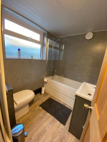 a bathroom with a toilet and a tub and a window at Comfortable 2 bedroom home from home with parking in Nottingham