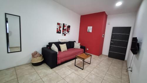 un soggiorno con divano e parete rossa di Amplio Dpto s/Av Rafael Nuñez - cerro de las rosas a Córdoba