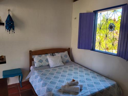 a bedroom with a bed with a blue comforter and a window at Chalé Flor do ser in Canoa Quebrada