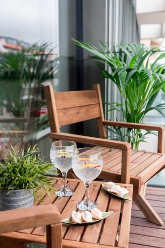 a wooden table with two wine glasses on it at Lux 56 Praia da Barra Aveiro A 20 metros da Praia in Praia da Barra