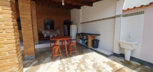 eine Terrasse mit zwei Hockern, einem Waschbecken und einem Tisch in der Unterkunft Casa Temporada Guriri Beira-Mar in Guriri
