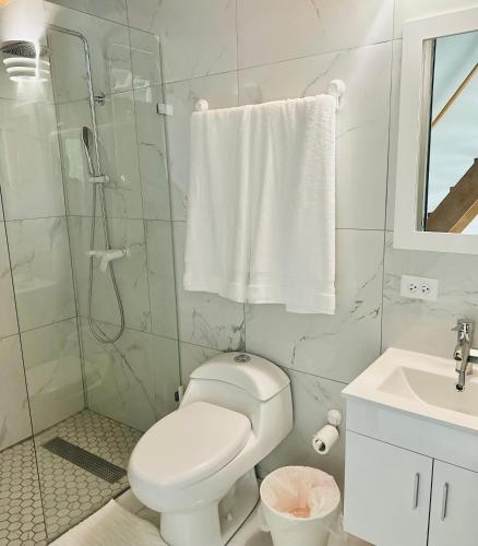 a white bathroom with a toilet and a shower at The Tiny Village Couple Retreat in Cabo Rojo