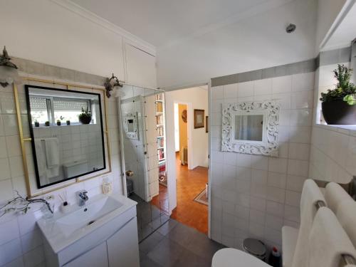 uma casa de banho branca com um lavatório e um espelho em Friends'house - azores em Rosário-Lagoa