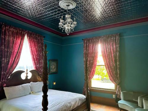 a bedroom with a bed with red curtains and a chandelier at The Mansion on 17th, formerly Schaefer Haus in Galveston