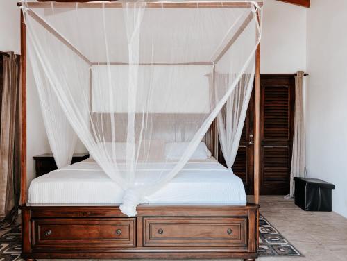 a bedroom with a canopy bed with white sheets at Moringa Villa Master Suite in Soufrière