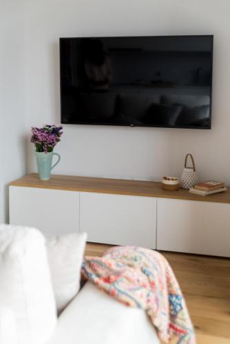 a living room with a white couch and a television on a wall at Lux 56 Praia da Barra Aveiro A 20 metros da Praia in Praia da Barra