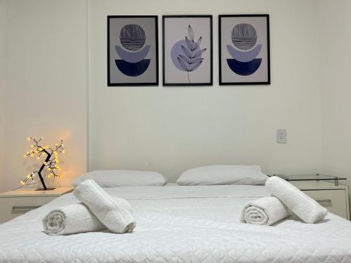 a bedroom with a bed with three pictures on the wall at Apartamento 3 quartos e boas energias in Balneário Camboriú