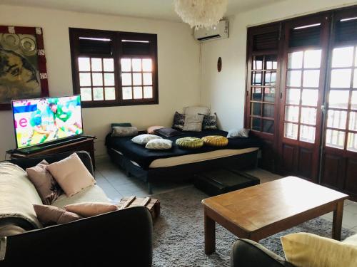 a living room with a couch and a tv at Chambre d'hôtes MAÏ TAÏ 4 personnes Bas du Fort in Le Gosier