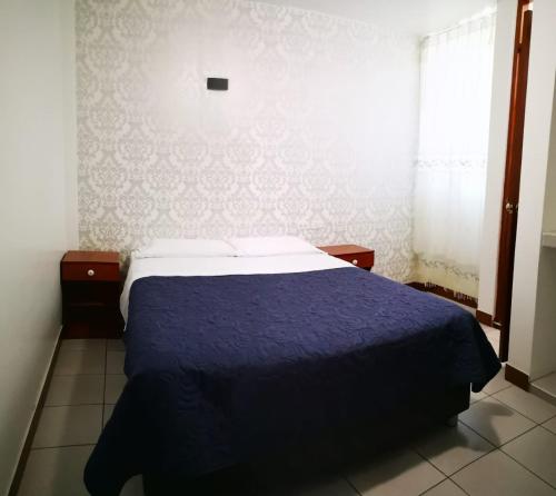 a bedroom with a bed with a blue comforter at La Posada Norteña in Lambayeque