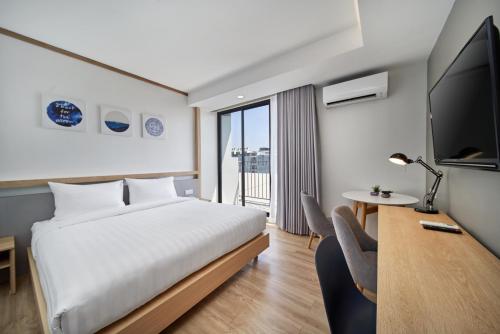 a hotel room with a bed and a tv and a desk at Prom Hotel in Bangkok