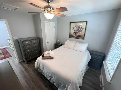 Schlafzimmer mit einem weißen Bett und einem Deckenventilator in der Unterkunft Charming Duplex on Main in St. Charles