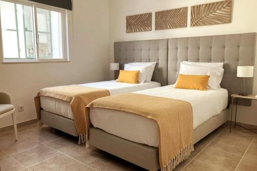 two beds in a hotel room with orange pillows at Villa with pool and sea view with two independent floors in Faro