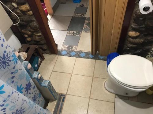 baño con aseo y suelo de baldosa. en Casa Sol y Luna, en Villa General Belgrano